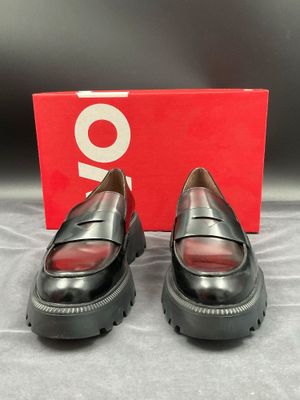 des chaussures à semelles compensées noires avec des semelles rouges et une boîte rouge
