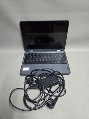 un ordinateur portable posé sur une table, à côté d'un chargeur