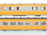 two trains that are sitting side by side on a white surface