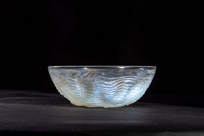 a glass bowl sitting on a table with a black background