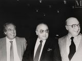 photographie en noir et blanc de trois hommes en costume et cravate, debout côte à côte