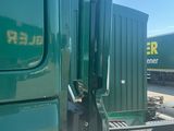 a green semi truck with a green trailer behind it