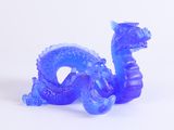 une figurine de dragon bleu posée sur une surface blanche
