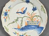une assiette bleue et orange décorée d'un oiseau et de fleurs