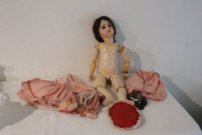 a doll that is sitting on a bed with clothes on it