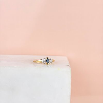 Une bague en or sertie d'un saphir bleu repose sur un bloc de marbre