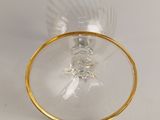 a wine glass with a gold rim on a white table
