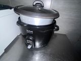 une mijoteuse noire et argentée posée sur le plan de travail de la cuisine