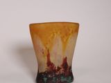 un petit vase posé sur une surface blanche