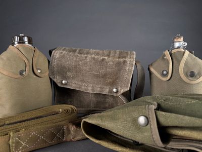 three flasks, a flask bottle, and a wallet are sitting on a table