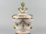a white and blue vase with a lid on a table