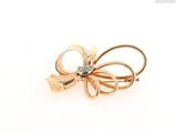an image of a gold bow brooch with a diamond in the center