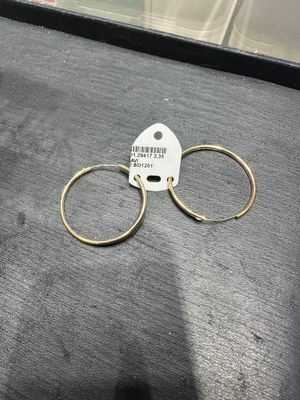 un gros plan sur une paire de boucles d'oreilles créoles en or posées sur une table