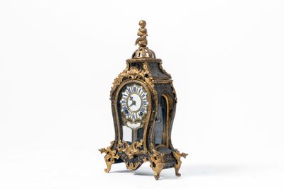 une petite horloge posée sur une surface blanche
