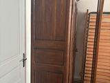 a tall wooden cabinet next to a mirror in a room
