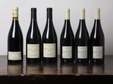 six bottles of wine are lined up on a wooden table