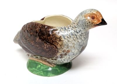 a ceramic bird on a green base with a white background