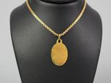 a necklace with a gold disc on a black mannequin