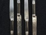 four knives are lined up on a black surface