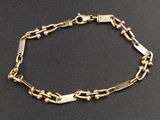 gros plan d'un bracelet en or sur une surface noire