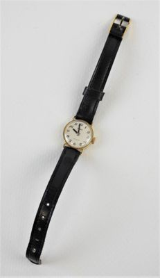 gros plan d'une montre sur une surface blanche avec un bracelet noir