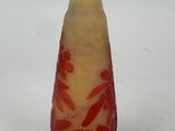 un vase rouge et jaune posé sur une surface blanche