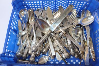 beaucoup de cuillères et de fourchettes en argent dans un panier bleu