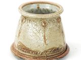 a close up of a small vase on a white surface