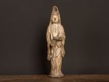 Une statue représentant une femme en robe blanche trône sur une table en bois.