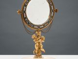 une image représentant un miroir orné d'un ange, posé sur un socle