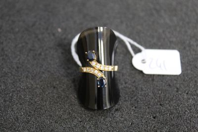 bague noire et dorée sertie de diamants, posée sur une surface noire à côté d'une étiquette de prix