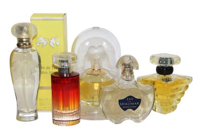 plusieurs flacons de parfum différents et une boîte de parfum posés sur une surface blanche