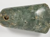 a green vase with a hole in it on a white surface