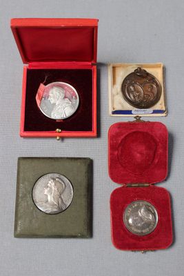 trois médailles d'argent et un écrin en velours rouge posé sur un fond gris