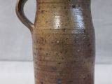 a brown vase with a handle on a table