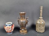 trois vases et une bouteille posés les uns à côté des autres sur une table