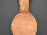 an old clay vase with a handle on a black surface