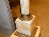 a marble column with a metal base in the middle of a room
