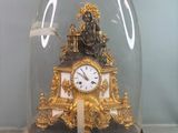 une horloge en or sous un dôme de verre sur une table