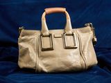 sac à main en cuir beige sur fond de velours bleu