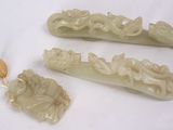 trois pièces de jade sculpté sont posées sur une surface blanche