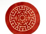 un tapis rond rouge orné d'un motif blanc