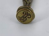 a small metal object with a gold seal on top of it