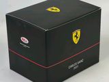 La boîte est noire, avec des bordures rouges et un logo Ferrari dessus.
