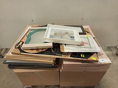 une pile d'œuvres d'art encadrées posées sur une palette dans une pièce