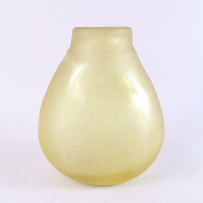 un vase jaune posé sur une surface blanche