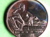 une pièce d'argent sur laquelle figure une statue, posée sur un fond vert