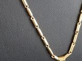a close up of a gold necklace with a bird on it