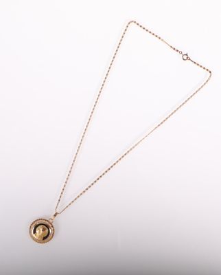 un collier en or avec une pièce suspendue à une chaîne, sur fond blanc