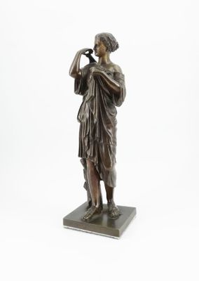 statue en bronze d'une femme tenant un oiseau sur un socle en marbre